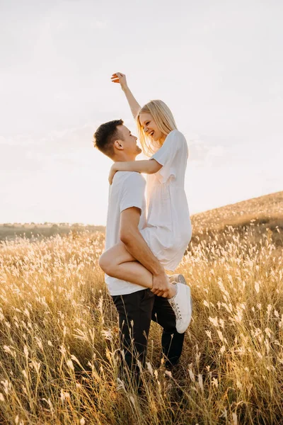 美丽的年轻夫妇在日落时分拥抱在草地上 — 图库照片
