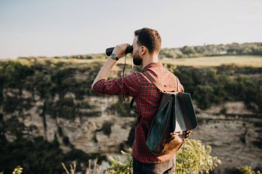 Deri çantalı ve dürbünlü yakışıklı bir genç adam portresi.