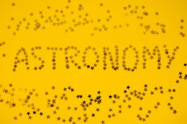 Kelime astronomisinin yakın plan görüntüsü sarı arka planda serpiştirilen yıldızlardan oluşturuldu