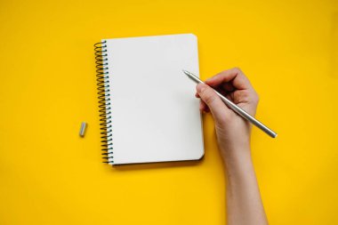 Sarı arkaplandaki boş defterin üzerinde el ele tutuşma.