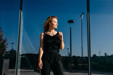 Şehir caddesinde şık kıyafetler içinde güzel genç bir kadın.