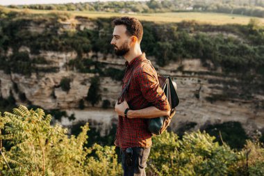 Doğada deri çantalı yakışıklı genç bir adamın portresi.