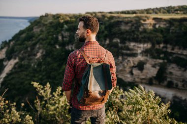 Doğada deri çantalı yakışıklı genç bir adamın portresi.