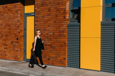 Caddedeki güzel genç kadın kırmızı tuğla duvarın önünde