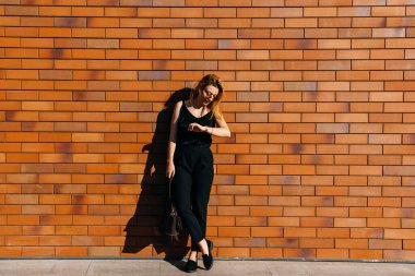 Caddedeki güzel genç kadın kırmızı tuğla duvarın önünde