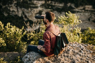 Doğada dürbünü olan yakışıklı bir gencin portresi.