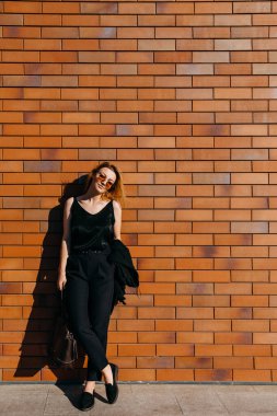 Caddedeki güzel genç kadın kırmızı tuğla duvarın önünde