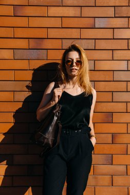 Caddedeki güzel genç kadın kırmızı tuğla duvarın önünde