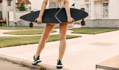 Sokakta uzun sörf tahtası olan bir kadın.