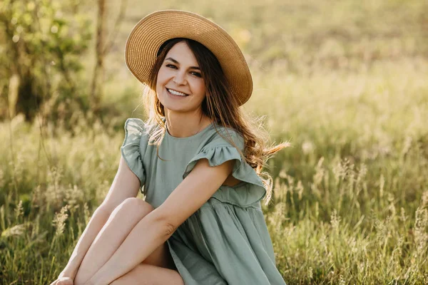夕日のりんご園のドレスとわらの帽子の美しい若い女性 — ストック写真
