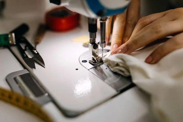 cropped shot of tailor sewing wedding dress in workshop