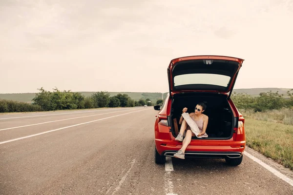 Genç Bir Kadın Elinde Haritayla Araba Bagajında Oturuyor Yaz Tatilinde — Stok fotoğraf