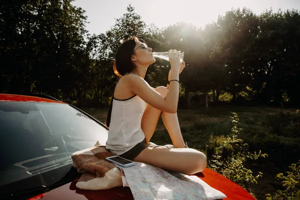 Bella Giovane Donna Rilassante Acqua Potabile Sul Cofano Dell Auto — Foto Stock