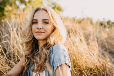 Doğada akşam vakti şık giyinmiş güzel bir genç kadının portresi.