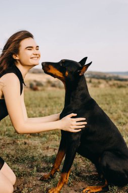 Doberman köpeğiyle vakit geçiren güzel bir kadının portresi.