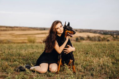 Doberman köpeğiyle vakit geçiren güzel bir kadının portresi.