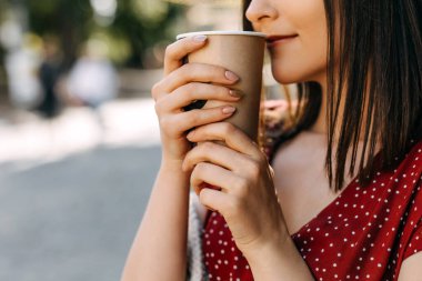 Sokakta elinde bir fincan kahveyle güzel bir genç kadının portresi.