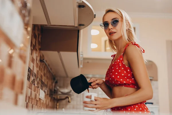 美しい若い女性作るコーヒーオンキッチンでセクシー赤トップとショートパンツ — ストック写真