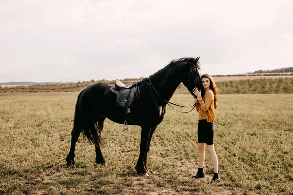 自然の中で黒い馬を持つ美しい女性の肖像画 — ストック写真