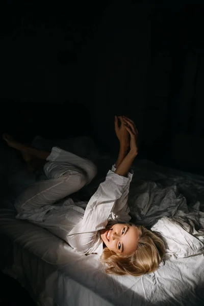パジャマ姿の美しい若い女性が朝ベッドでリラックスして — ストック写真