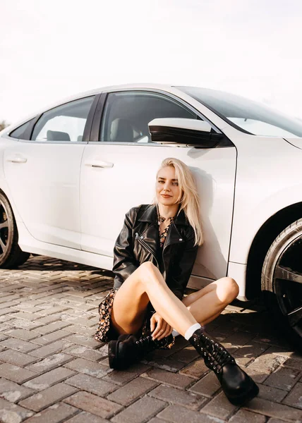 beautiful young woman sitting in front of her car on parking