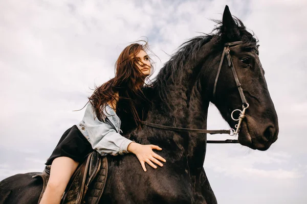 自然の中で黒い馬に乗って美しい女性の肖像画 — ストック写真