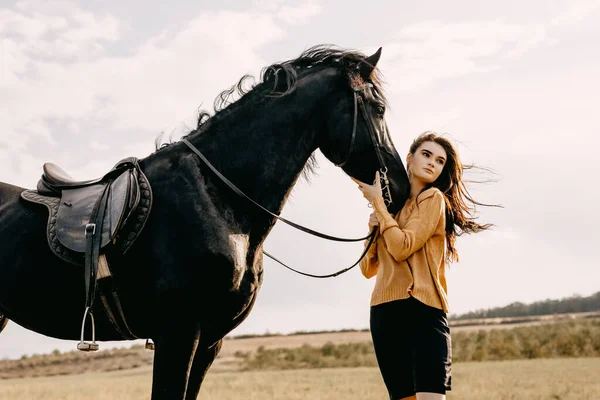 自然の中で黒い馬を持つ美しい女性の肖像画 — ストック写真