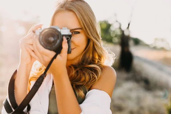 portrait of beautiful young female photographer with vintage camera on nature