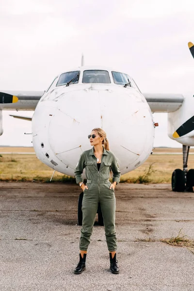 portrait of beautiful blonde pilot woman in front of airplane