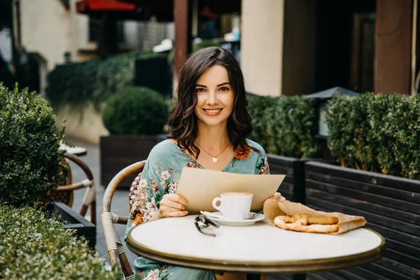portrait of beautiful young woman with cup of coffee relaxing in street cafe