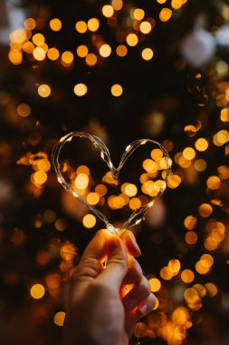 Bulanık arka planda peri ışıklarından yapılmış bir kalp..