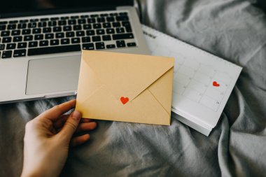 Diz üstü bilgisayarda kalbi olan sarı bir zarf tutuyordu.