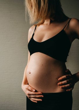 Sıska hamile bir kadının göbeğinde el ele tutuşması..