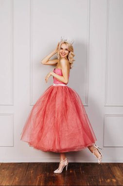 Pembe tül elbise ve taç giyen, gülümseyen, mutlu ve çekici genç bir kadın..