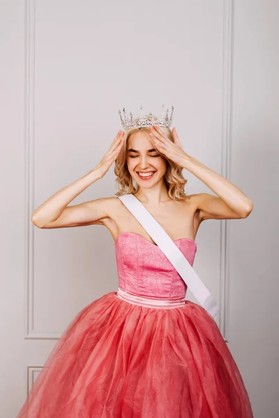 Happy Young Blonde Woman Wearing Crown Pink Dress White Ribbon Stock Photo  by ©nataliabostan 444262926