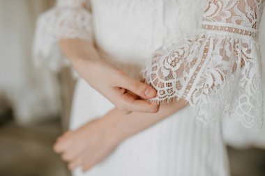 Gelinlik giymiş bir gelinin, dantel kollarını düzeltirken yakın çekimi..