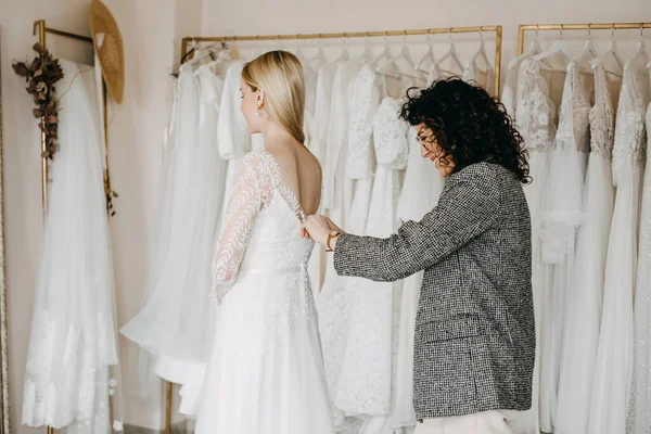 花嫁がウェディングドレスを着るのを助けるファッションデザイナー — ストック写真