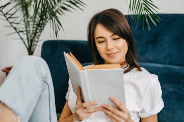 Genç esmer kadın beyaz kapaklı bir kitap okuyor, yakın plan..