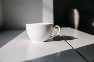 Boş bir fincan kahve ya da güneş ışığında pencere kenarında çay..