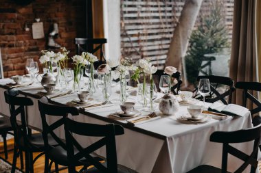 Çiçekler ve sofra takımlarıyla süslenmiş bir restoranda masa..