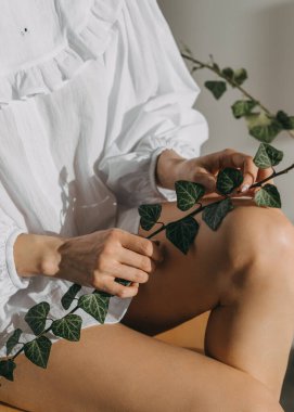 Elinde yeşil yapraklar olan bir dal tutan bir kadının yakın çekimi..