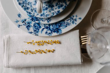 Mimoza dallarının peçeteyle yakın plan Çin porselen bardağı ve tabaklarının yanında..