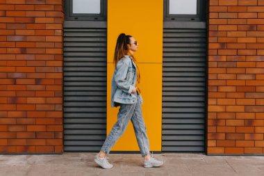 Kot pantolon giyen, sokaklarda yürüyen genç bir kadın..