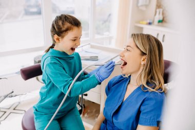 Diş kliniğinde hastası olan küçük bir kız doktor dişlerini kontrol ediyor.. 