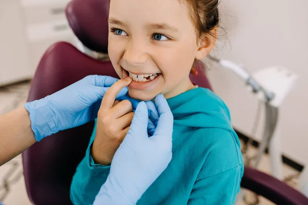 Child at a dental clinic. Girl showing bad tooth to a dentist.