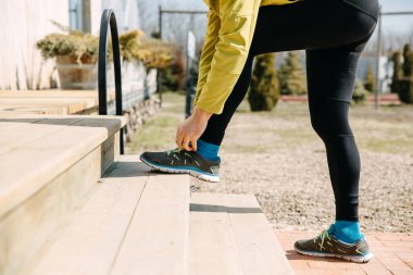 Ayakkabı bağcıklarını tahta merdivenlerde bağlayan koşucunun yakın çekimi. Koşmaya hazırlanıyorum..