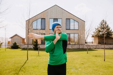 Aktif adam sabahları dışarıda, arka bahçede çalışıyor. Kollarını uzatan adam.