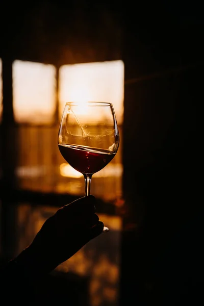 Γυναικείο Χέρι Κρατώντας Ένα Ποτήρι Κόκκινο Κρασί Στο Φως Του — Φωτογραφία Αρχείου