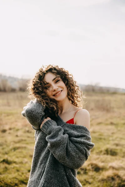 Šťastná Mladá Žena Kudrnatými Vlasy Usmívající Oblečená Přerostlém Svetru Poli — Stock fotografie