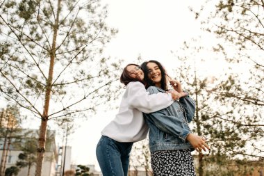 İki kız kardeş, dışarıda eğleniyorlar, sarılıp gülüyorlar. En iyi arkadaş konsepti.